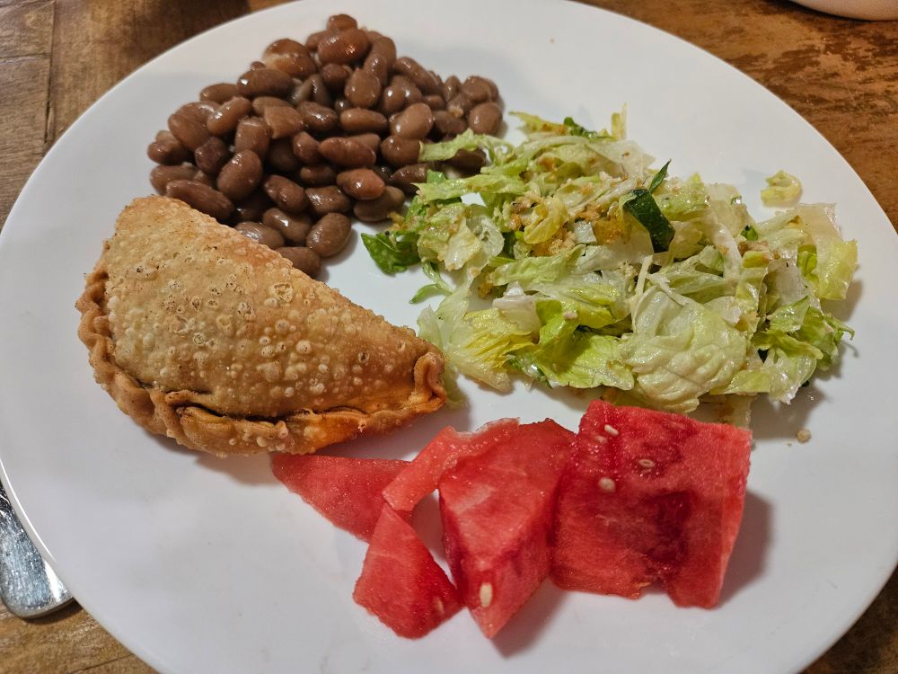 My lunch plate: picadillo empanada, pinto beans, salad, watermelon 