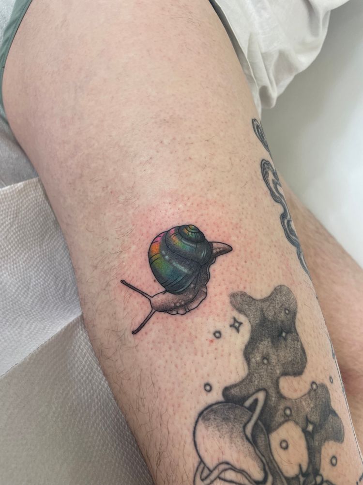 A tattoo of a snail with an iridescent shell