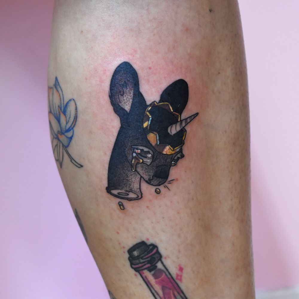 A tattoo of a deer-like black unicorn severed head with a metallic gold crown, gold tears drip from its large eye 