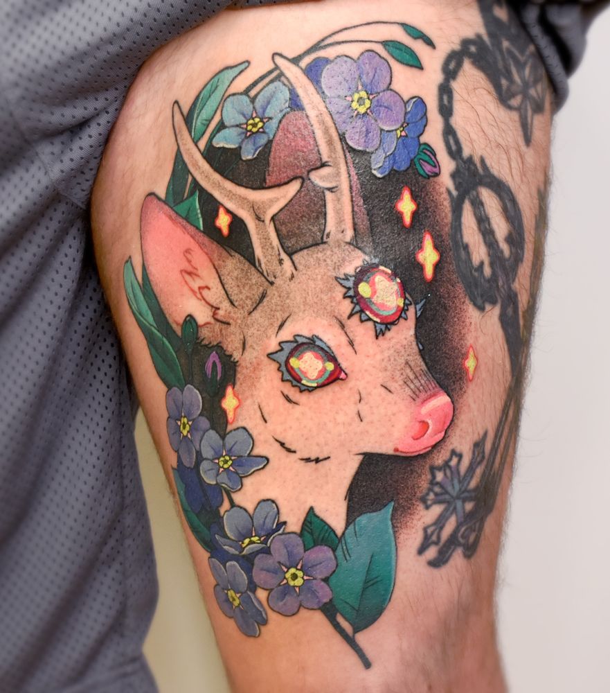 A large scale colour tattoo in a neotrad inspired style of a deer with three neon eyes, surrounded by blue and purple florals and floating neon stars 