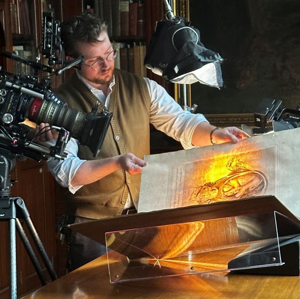 Curator of Rare Book Room at JHU's Institute of the History of Medicine, Michael Seminara holds up a page of Gabriele Fallopio’s Observationes anatomic (printed in Venice in 1561) for a documentary film crew. The page is backlit. 