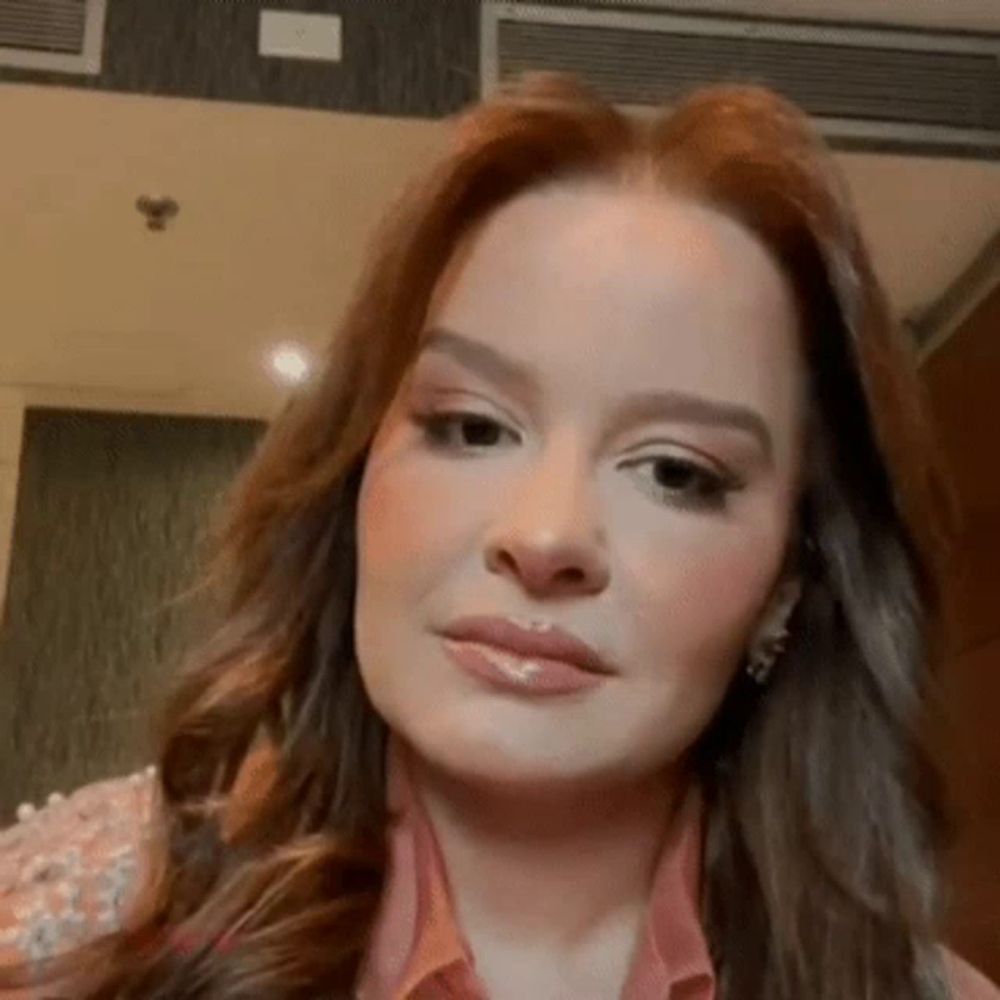 a close up of a woman 's face with long red hair and earrings .