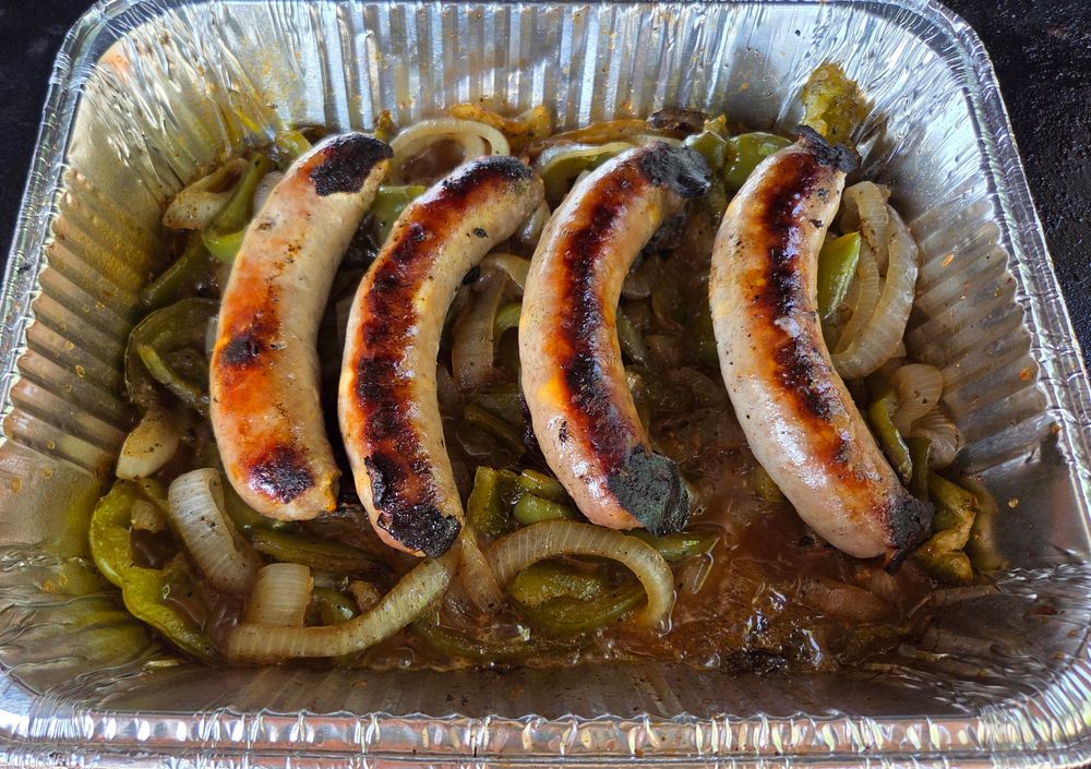 Local Berkshire pork cheddar bratwurst steaming in beer with local onions and green peppers.