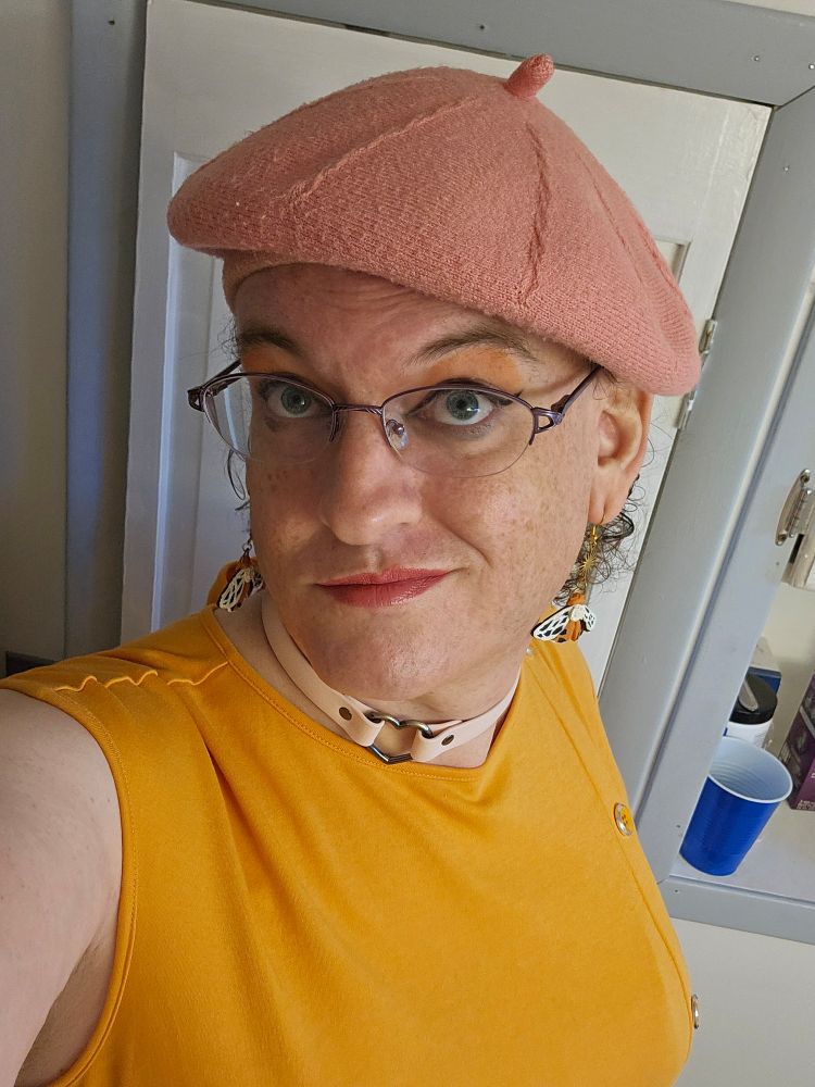 Cesena, wearing a pink beret and an orange sleeveless dress