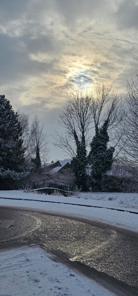 Sun in the sky surrounded by clouds appears like an eye looking down on the artistic landscape painted by medium of snow.