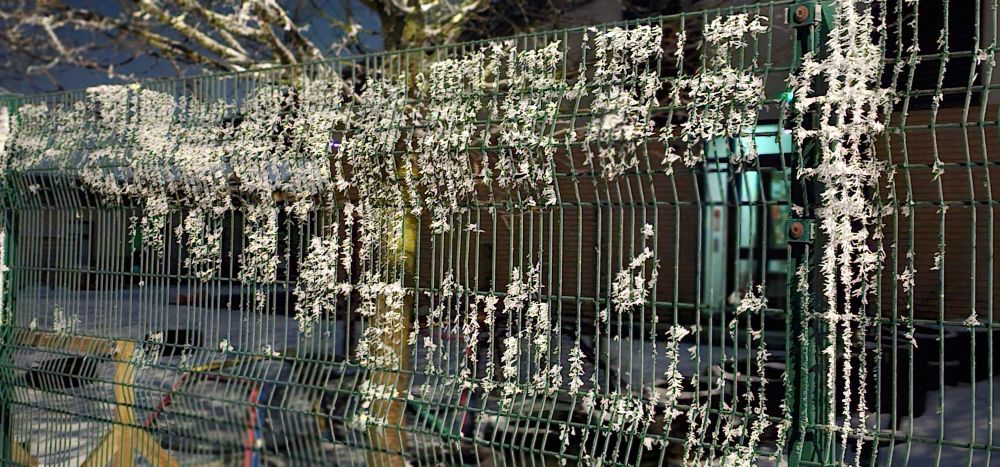 Snow deposited on metal fencing that appears like Christmas lighting