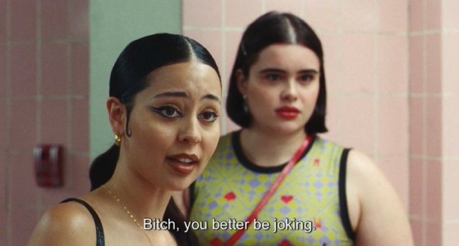 Scene from Euphoria with Maddie (long black hair, gold earrings and necklace, black dress) and Kat (short, dark hair, green tank with red hearts) in high school bathroom. "Bitch, you better be joking"