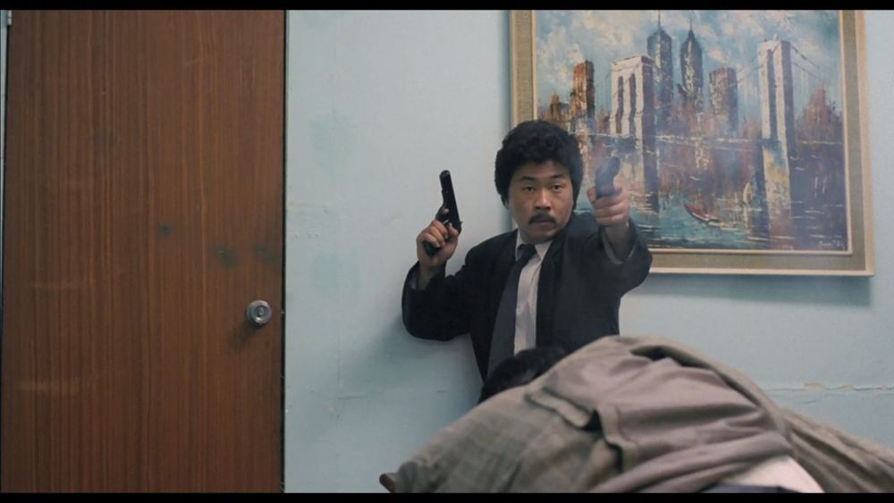 Scene from Tiger Cage. Johnny Wang shooting at coppers.