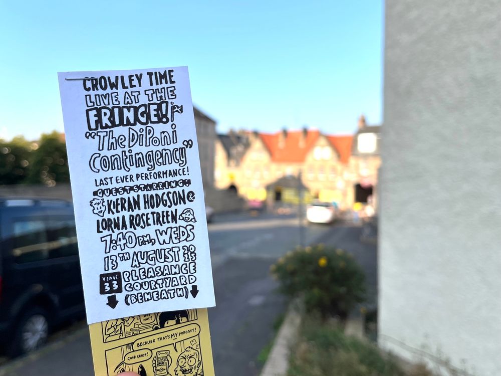 A flyer for Crowley Time Live held up in front of the distant Pleasance Courtyard. 