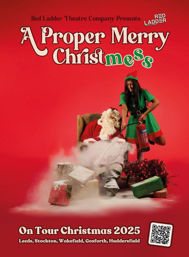 Poster for A Proper Merry Christmess. Red background. A young British South-Asian woman in a green elf costume spraying a sleeping Santa Claus in an armchair surrounded by gift boxes with a fire extinguisher.