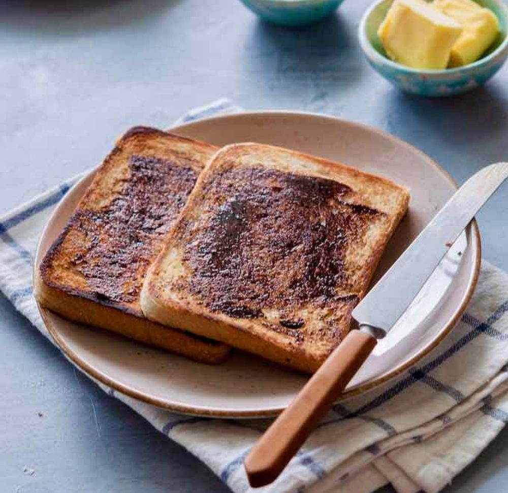 Vegemite toast, butter in a cruicable, and knife with some Vegemite on it on a small plate, on top of a blue and white checkered tea towel 