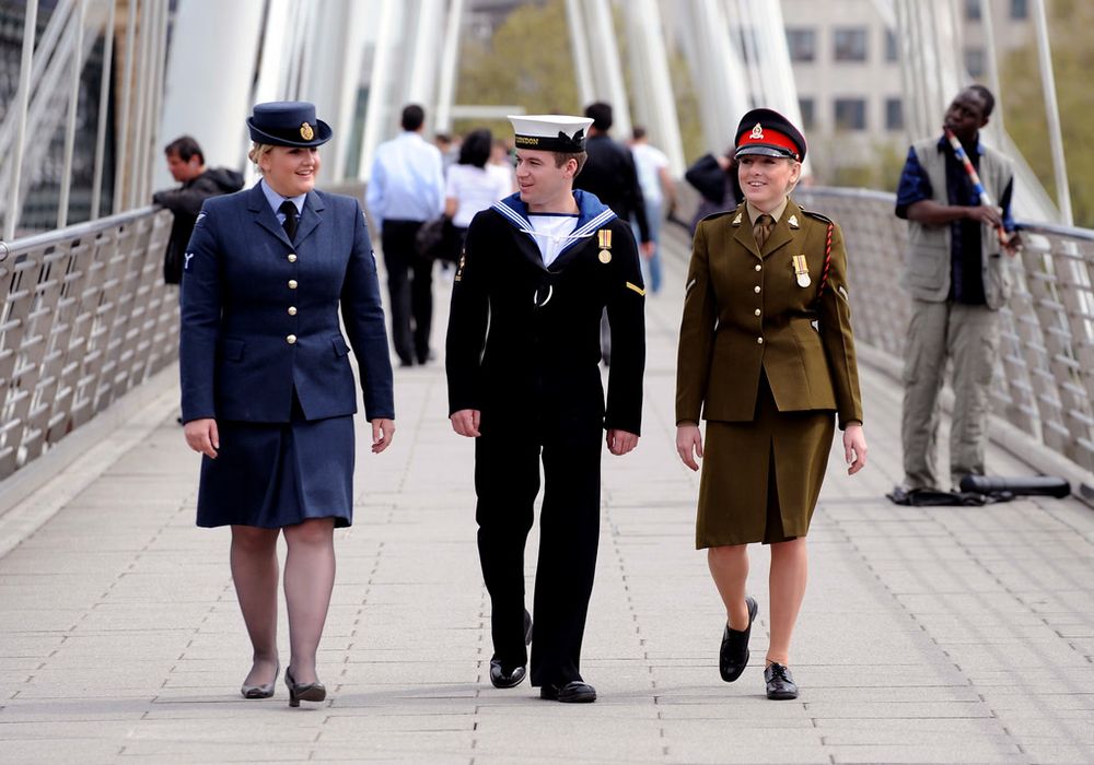 A trio of armed forces personnel crossing a bridge