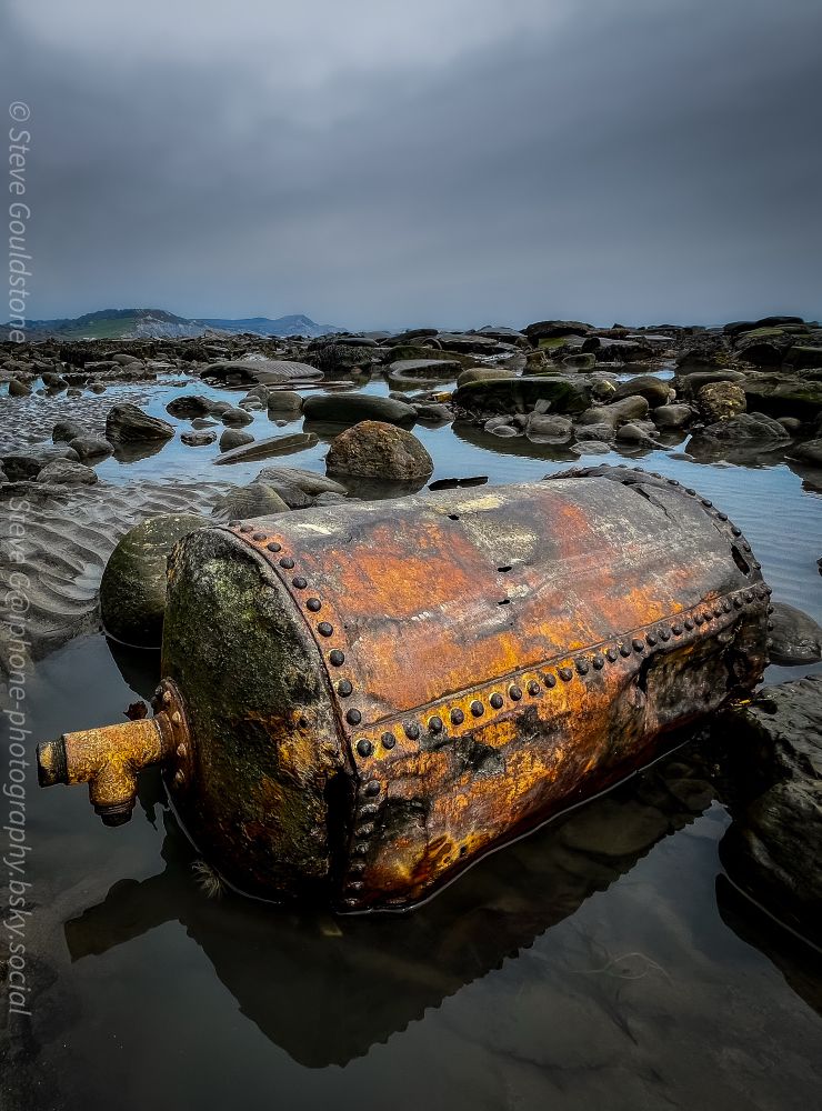 An old riveted water tank or boiler. 

As Lyme Regis cliffs crumble, the contents of an old rubbish dump fall into the sea.

Every new storm turns up something different - broken Victorian glass, ceramics & metal objects litter the shoreline. 

