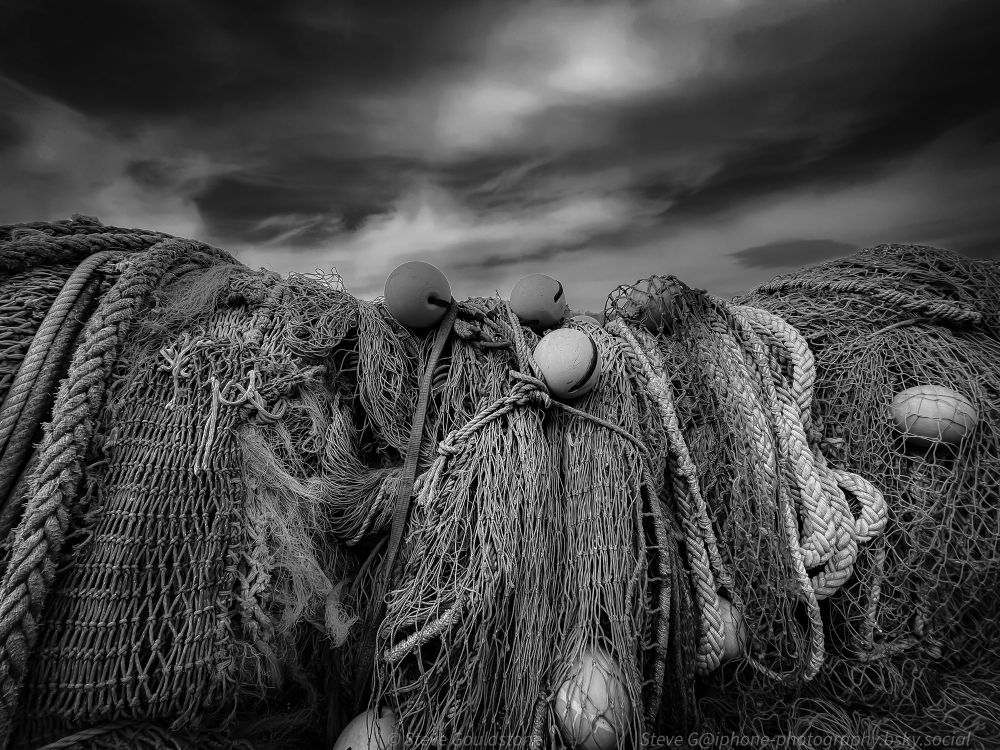 A jumble of ropes, nets and floats on the harbour side at Lyme Regis, Dorset. England. Mono version.