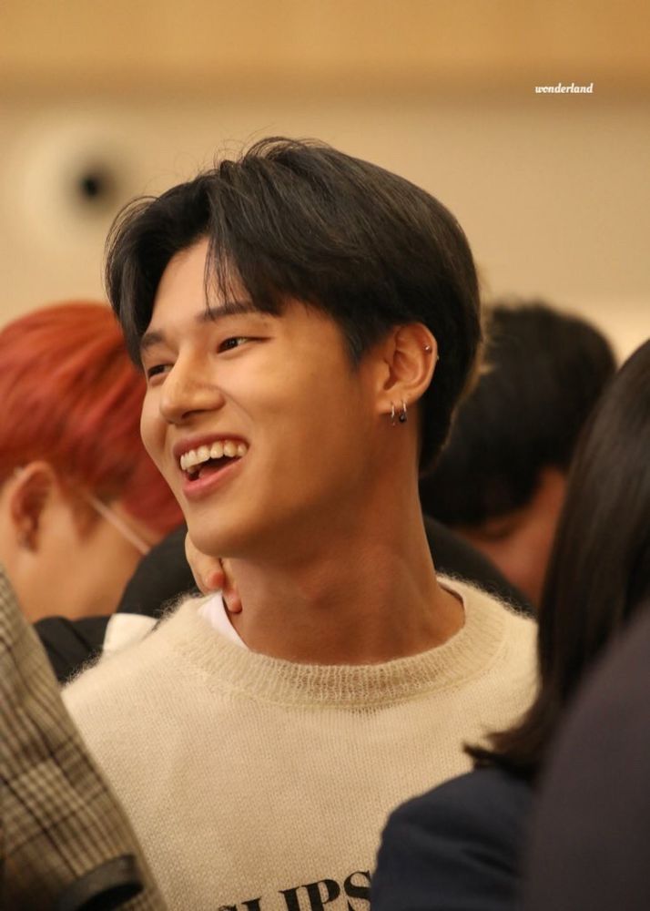 Jung Wooyoung of ATEEZ smiling at ATEEZ wearing a sweater - caption credits image to "wonderland"