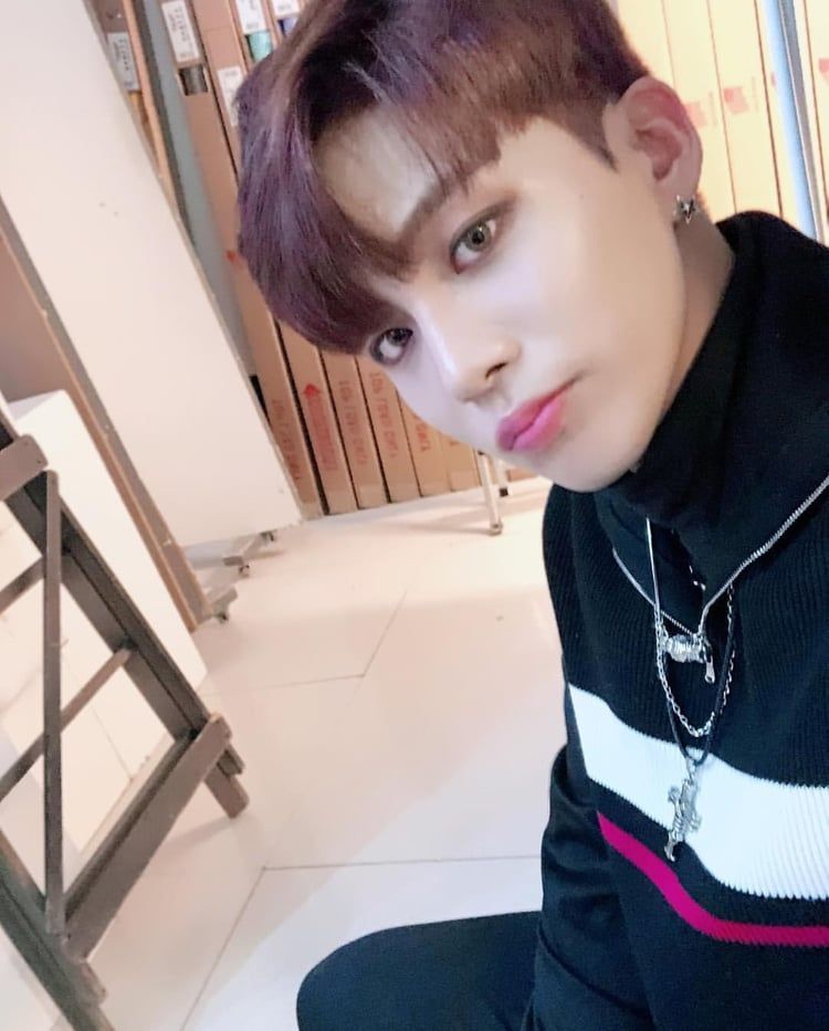 Choi Jongho of ATEEZ pouting at the camera wearing a black striped sweater