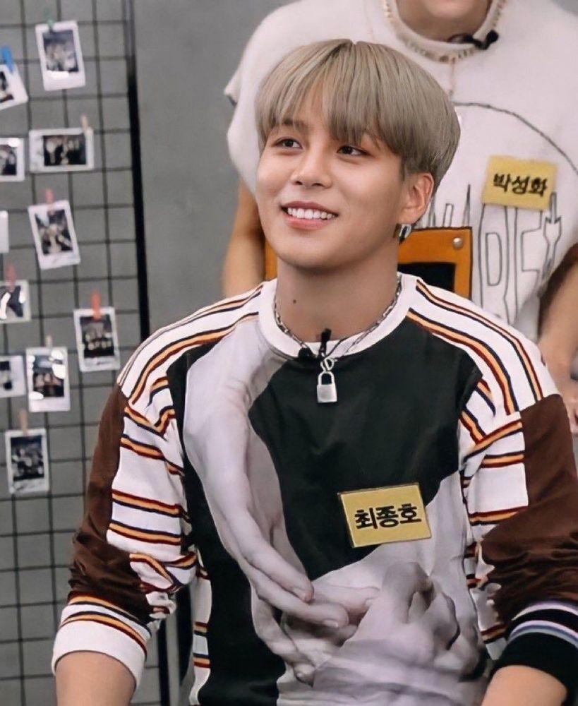 Choi Jongo (ATEEZ) with ashy blond hair wearing a graphic sweater smiling