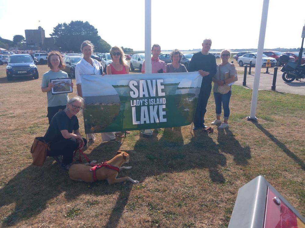 A group photo of volunteers at Lady’s Island Lake holding a banner. 