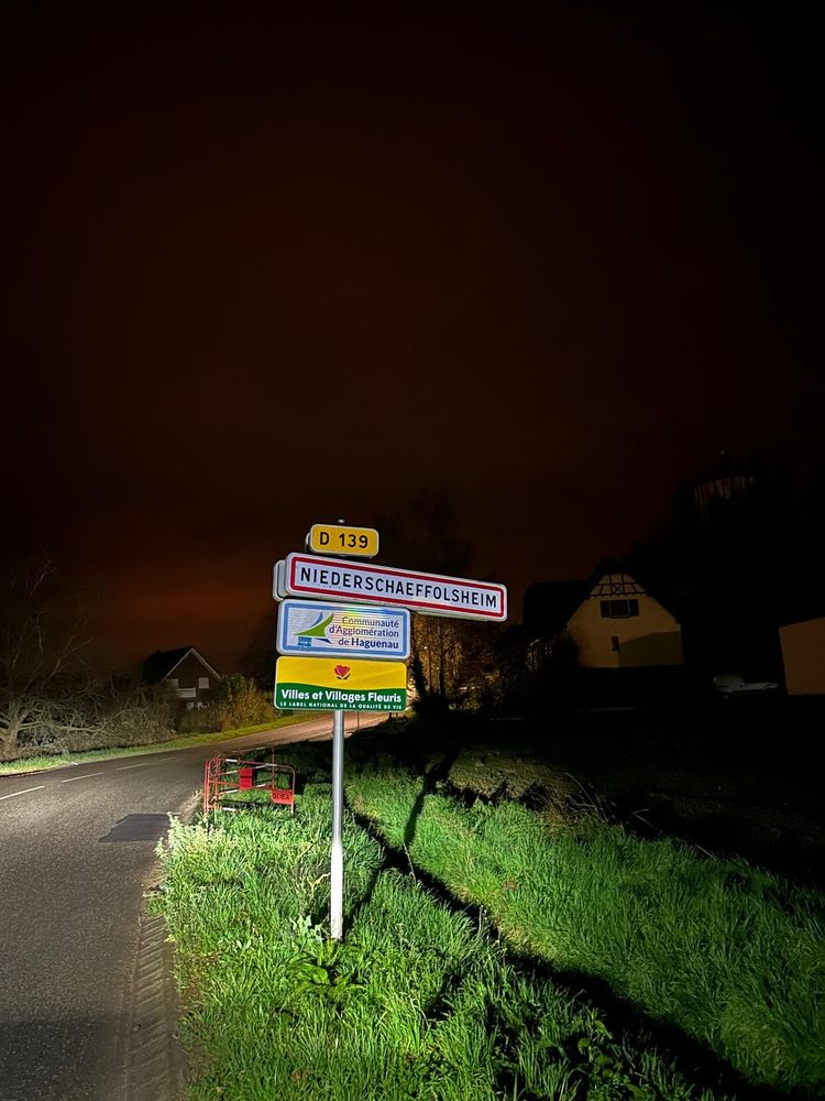 Panneau d'une ville alsacienne nommé "Niederschaeffolsheim" tellement long que le panneau penche un peu 