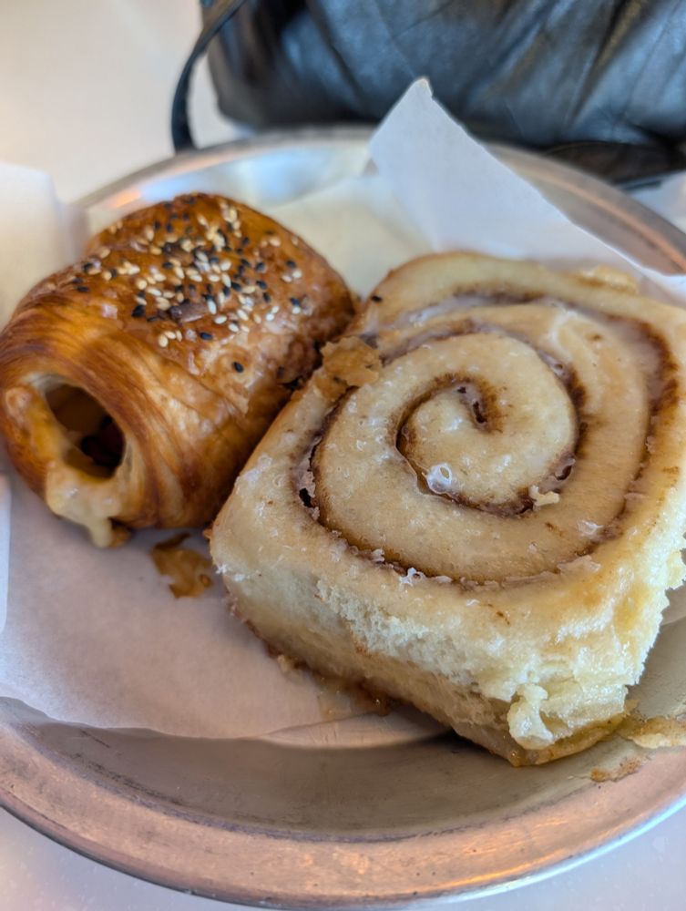 Photo of a large cinnamon roll and a ham and cheese croissant 