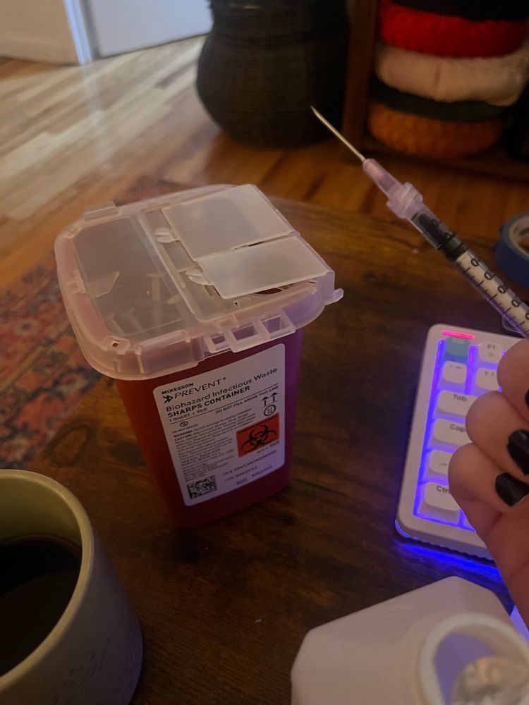 sharps container, my coffee, my keyboard, my hand holding a syringe filled with estradiol valerate