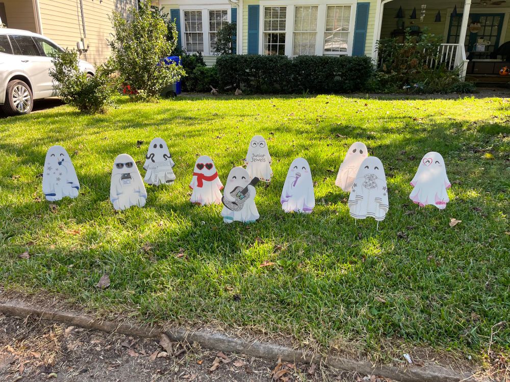 Yard decorated for Halloween. Full of 2D ghosts made from old yard signs painted white.
