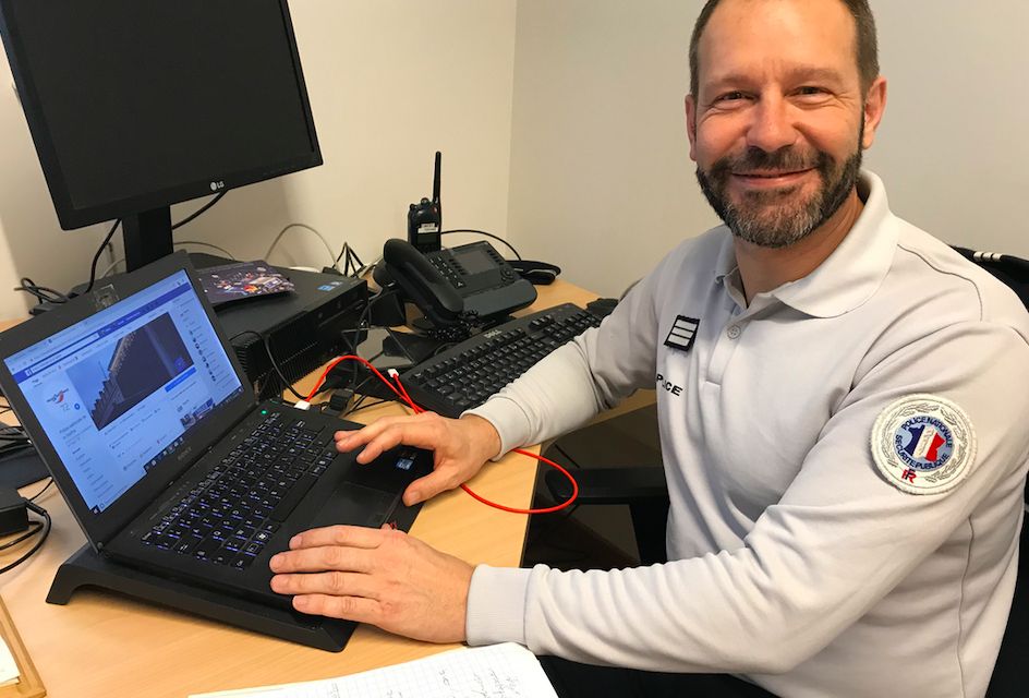 Policier souriant devant un ordinateur