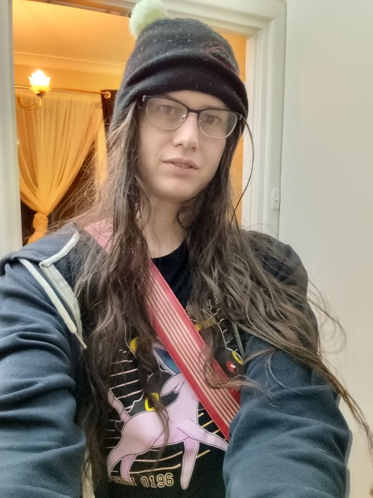 me. in a beanie. i look like a guy imo but some extremely people in the comments are going to disagree. mostly wearing shades of black, and an espeon/umbreon shirt