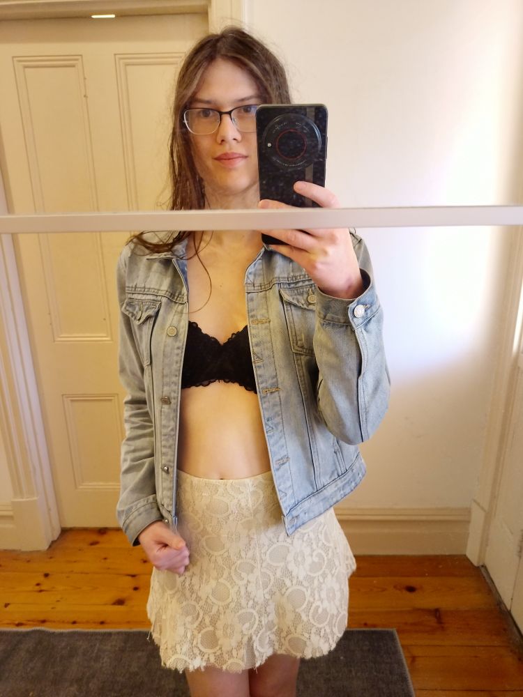 black bra under a denim jacket, and white lacey miniskirt