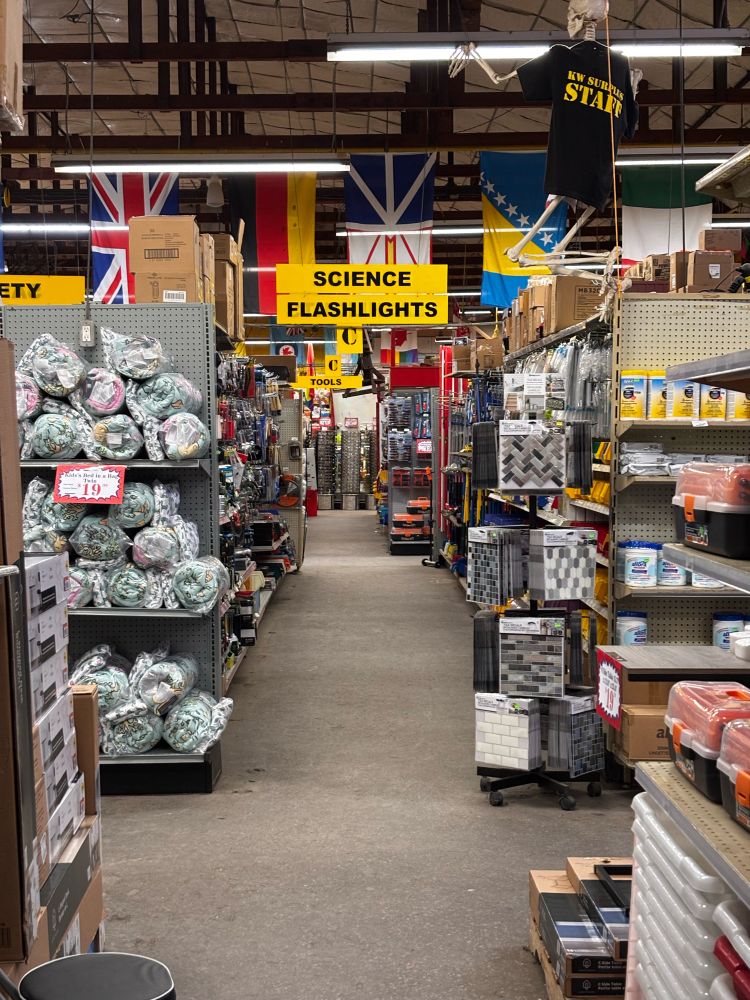 Interior view of an army surplus store featuring a ‘SCIENCE & FLASHLIGHTS’ aisle marker sign