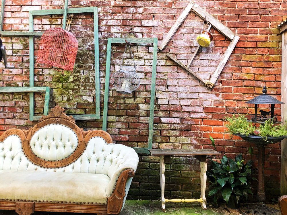 A quirky outdoor seating area with colorful decorative frames and a vintage couch