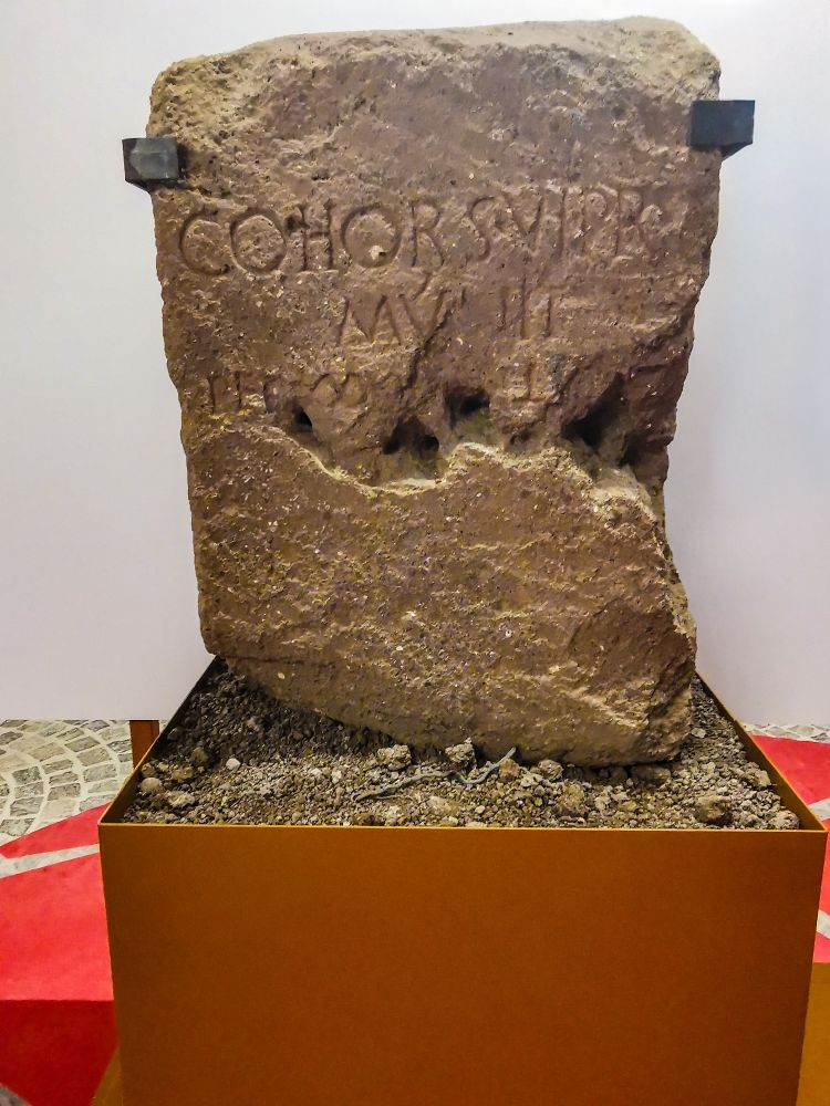 CIPPUS WITH INSCRIPTION, AFTER 6 CE. DRUGSTORE MUSEUM

COHORS VI PR(ÆTORIA) / MVNIT / PER P(EDES) ∞∞ [---]CLX[---?]

"The sixth Prætorian cohort made (this) for 2160 (Roman) feet". Damage to the third line makes other letters illegible. The numeration is not our familiar Roman numerals, but uses what we think of as the infinity symbol, ∞, in place of the more familiar M to indicate 1000. It's used twice here, so 2000. Then comes C, 1000, then the upside-down T which is an alternate for L, 50, and X, 10. Adding this up gives us a significant distance, 2160 feet or 640 metres, which probably refers to roadworks, or, less likely, hydraulic works, both of which fell into the purview of the Prætorians. The crumbly stone of the cippus is tufo lionato, or Monteverde tufo, distinguished by its yellow colour. 