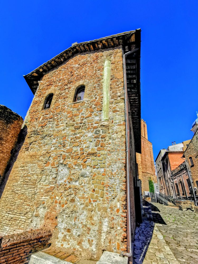 This photo shows the end of the series of Trajanic buildings rising over Trajan's Markets, with an ancient paved road beside it and the colossal Torre delle Milizie (c. 1200) visible at the end. The 1349 earthquake tilted the tower, and the tilt is still visible: the tremor also brought down the upper third of the tower. The side of the house we see here is built on the foundations of its Trajanic predecessor, and further along, other rooms still have their ancient brick interiors but have needed rebuilt medieval façades. Two spolia columns are embedded in this wall on the upper level, one at the front (to the right) and the other, of green Carystian cipollino, toward the street façade. 