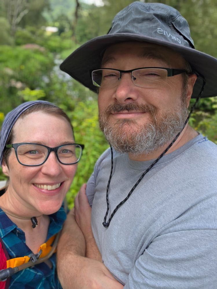 Two white people hiking on a trail. 