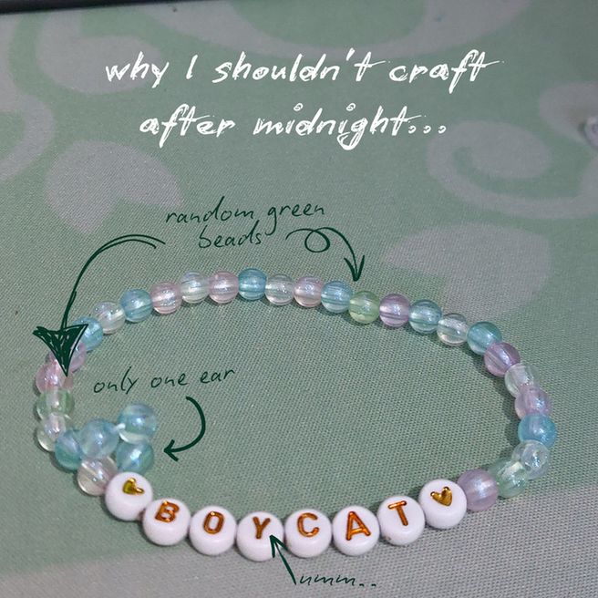 why I shouldn't craft after midnight. Picture of a trans colour candy bracelet with "boycat" written in the centre, and arrows point out problems. Random green beads, only one cat ear, "boycat" ummm