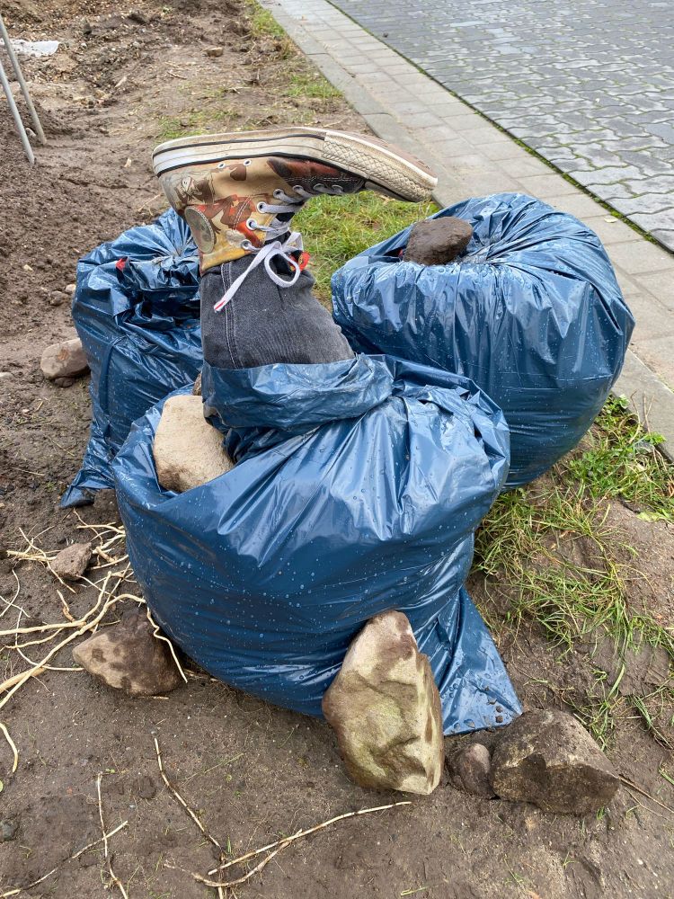 Some filled garbage bags, pants with an attached boot can be seen, stuck out of one of the bags.