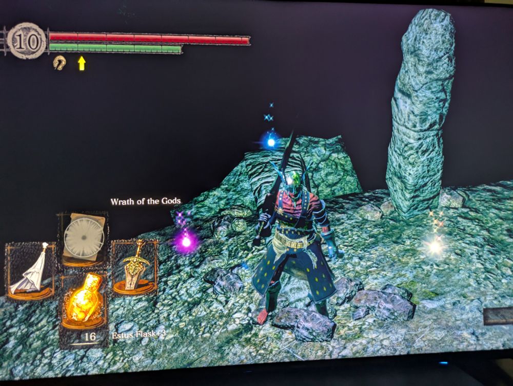 A picture of a television with an image from Dark Souls. There are three glowing stones in view; they are pink, blue, and white