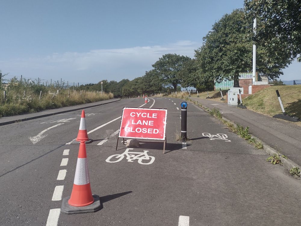 A sign saying 'Cycle Lane Closed' at the start of a section of segregated cycle lane currently being dismantled.