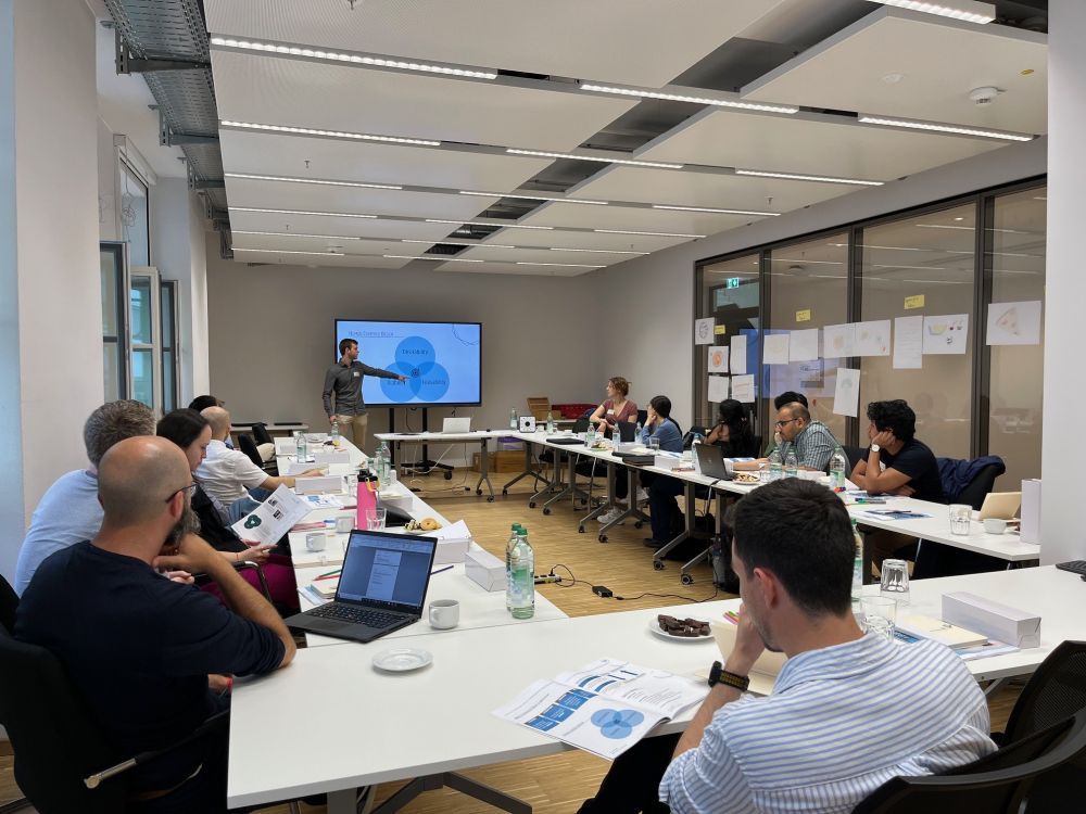 Participants of the Max Planck Startup School sitting in a modern workshop room.