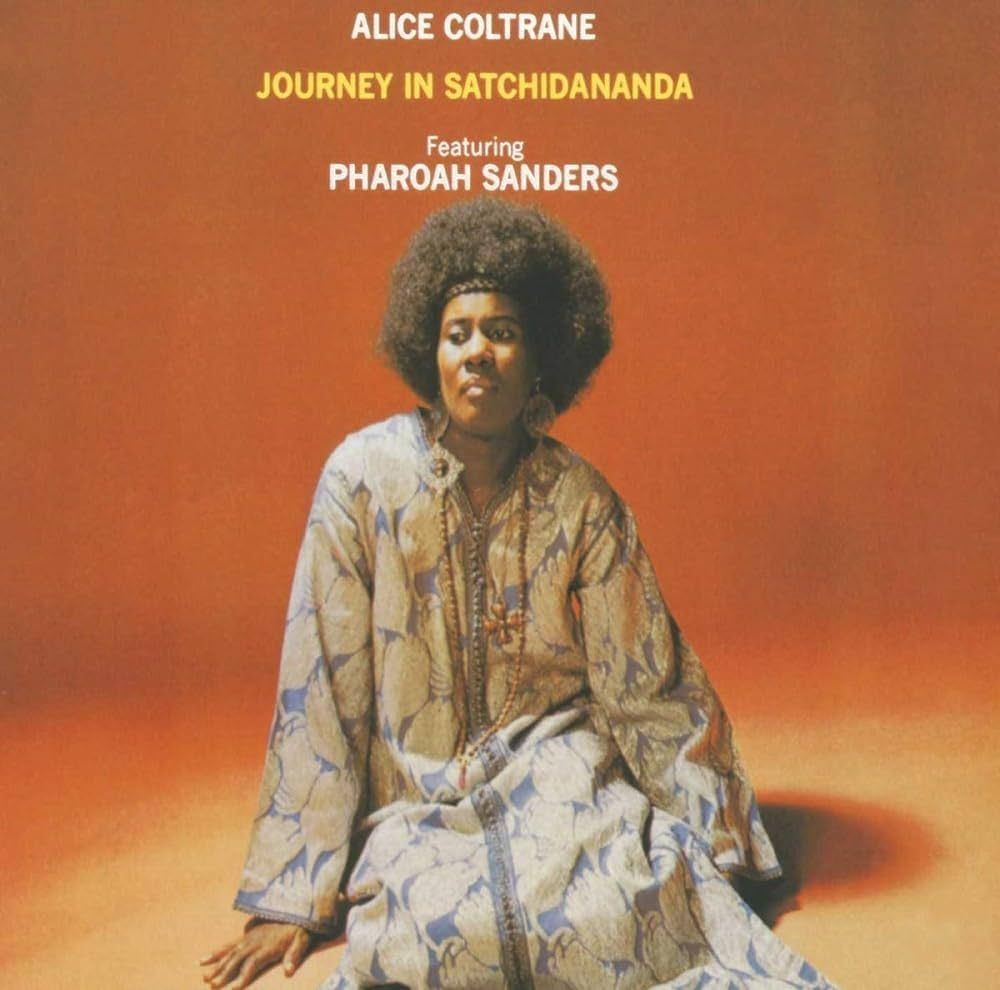 Alice Coltrane - Journey In Satchidananda album cover. The artist sat against an orange background.
