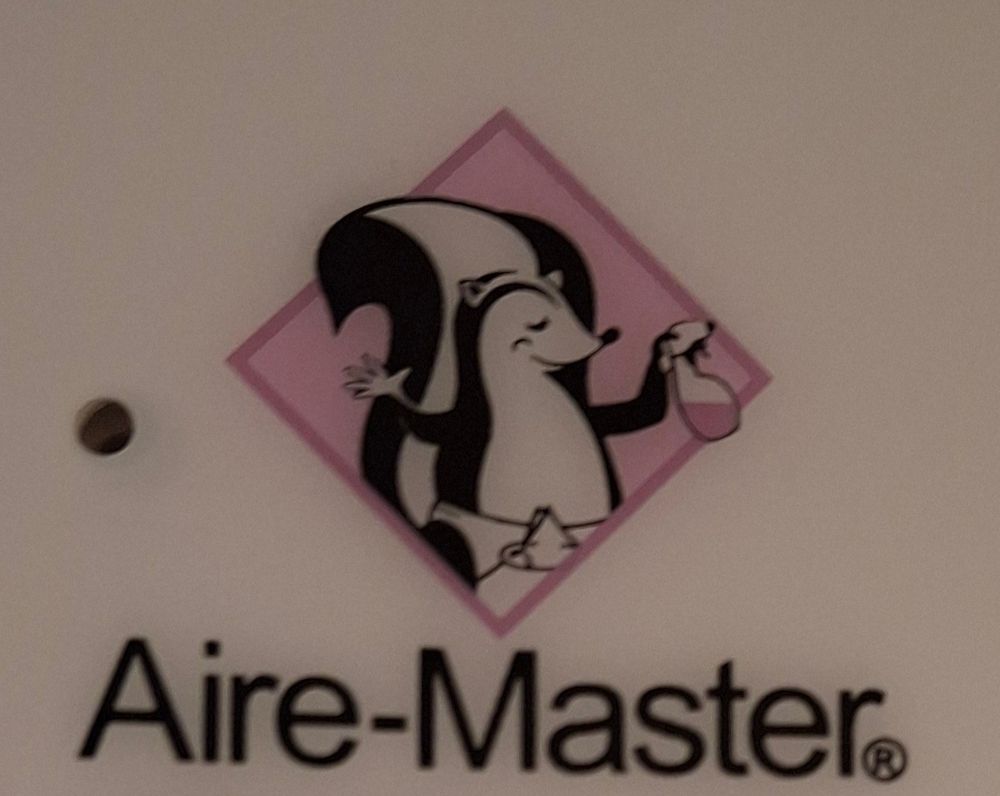 a photo of the aire-master mascot. he's a skunk wearing a safety pin diaper, ans holding a pink bottle of cleaning fluid. he smells good, probably? maybe he's always carrying air freshener for his BO [body odor]