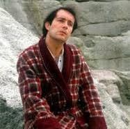 Arthur Dent in a dressing gown on a rock.