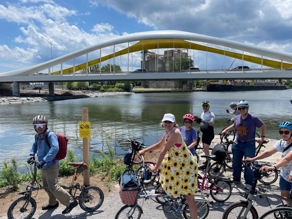 Brompton riders in front of the Cherry Street bridge in Biidaasige Park.