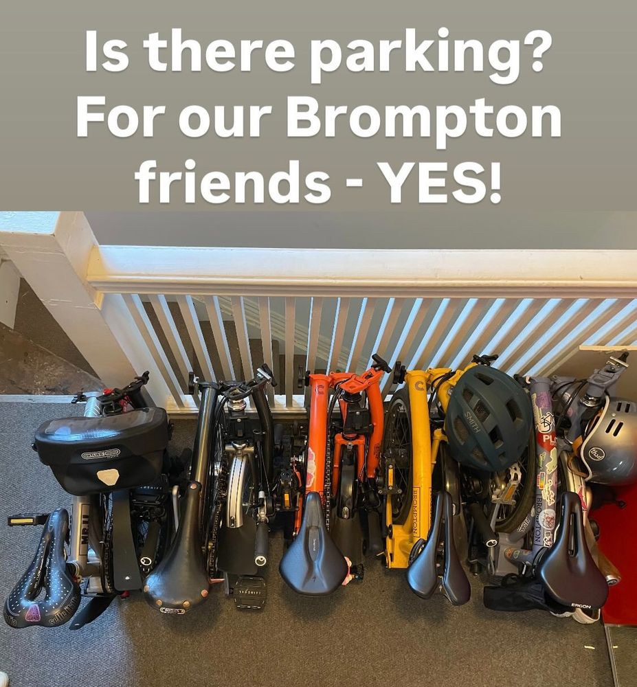 5 Brompton bikes folded on a landing at the top of a staircase.
