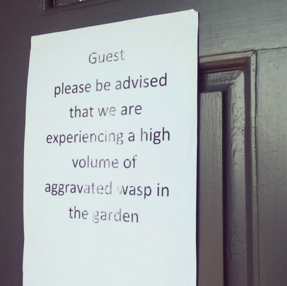 Sign that reads "Guest please be advised that we are experiencing a high volume of aggravated wasp in the garden"