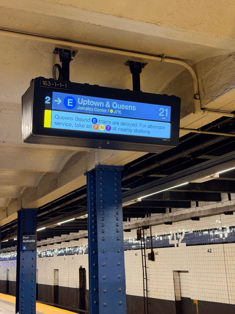 Metro signage showing the E train arriving in 21 minutes and also announcing E line uptown delays. 
