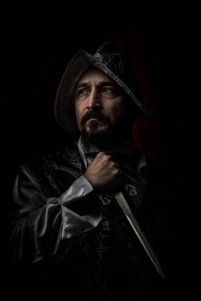 Godriguez wearing a Conquistador helmet hides in the shadows with his dagger in hand
