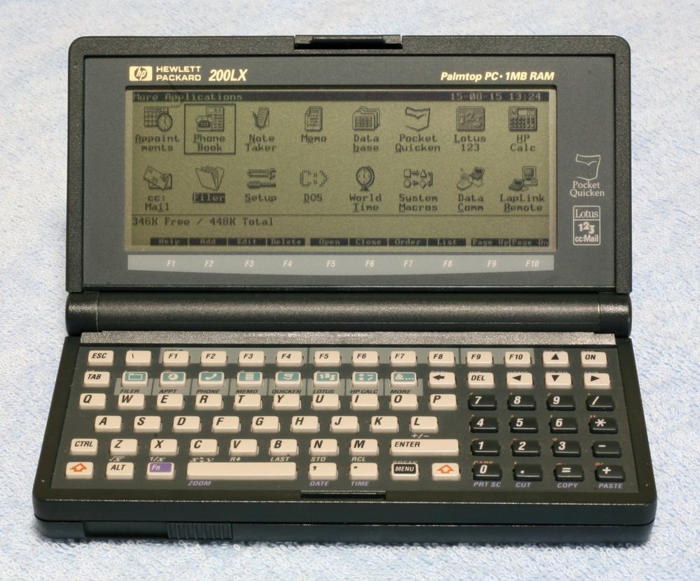 A grey clamshell handtop. Up top, the 640x200 monochrome screen has applications: Appointments, Phonebook, Note Taker, Memo, Database, Pocket Quicken, Lotus 123, HP Calc, cc:Mail, Filer, Setup, DOS, World TIme, System Macros, Data Comm, and Laplink remote, plus a memory tracker (346K Free/448K Total) and legend for the function keys. Down below, a micro-QWERTY keyboard with numb pad appears, with a second row of function keys to switch tasks between the isntalled apps and cursor keys above the numbpad. Image © Tamie49.