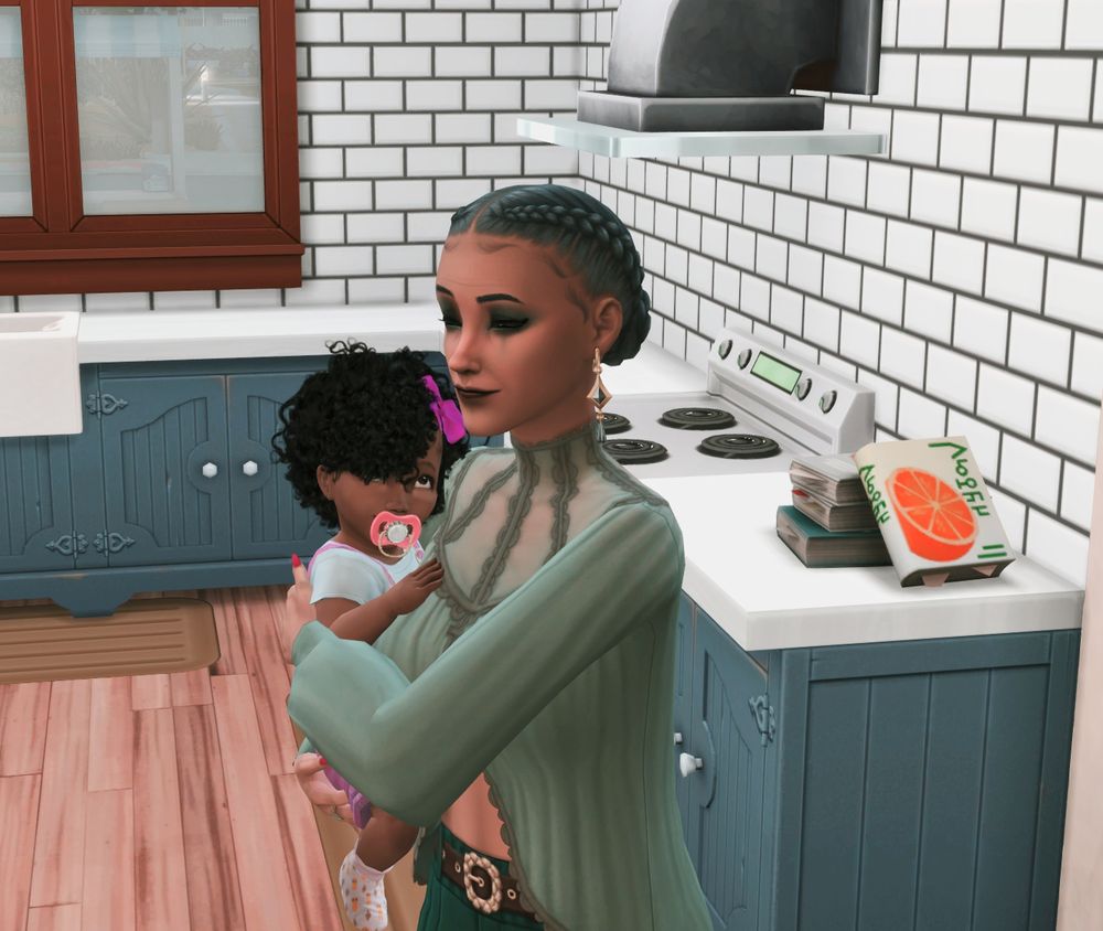 Natalie meets her Grandma Olive (aka Nyon's mother). Olive is wearing a green sheer top and has her hair braided and pulled back. Natalie is waring pink overalls with a white t-shirt underneath, she also has a bright pink binky in her mouth.