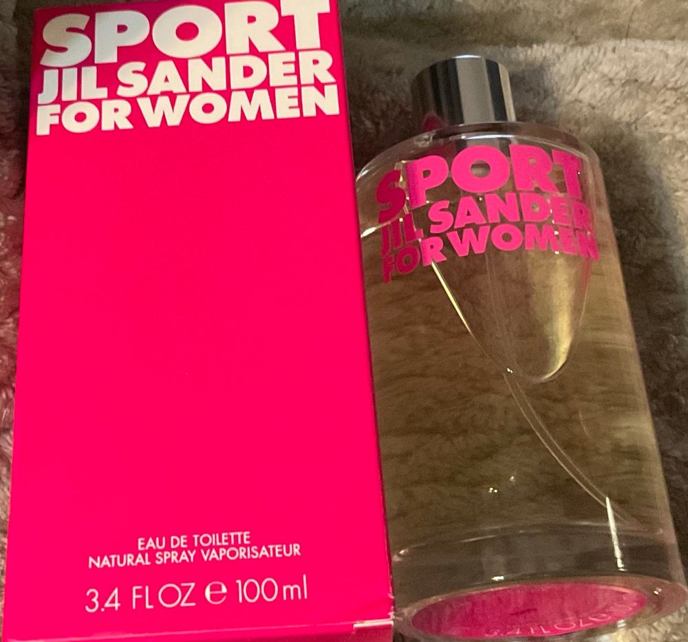 box and bottle of Jil Sander’s Sport For Women perfume which has clear juice in a glass bottle with pink lettering and a silver cap and the box is hot pink with white lettering